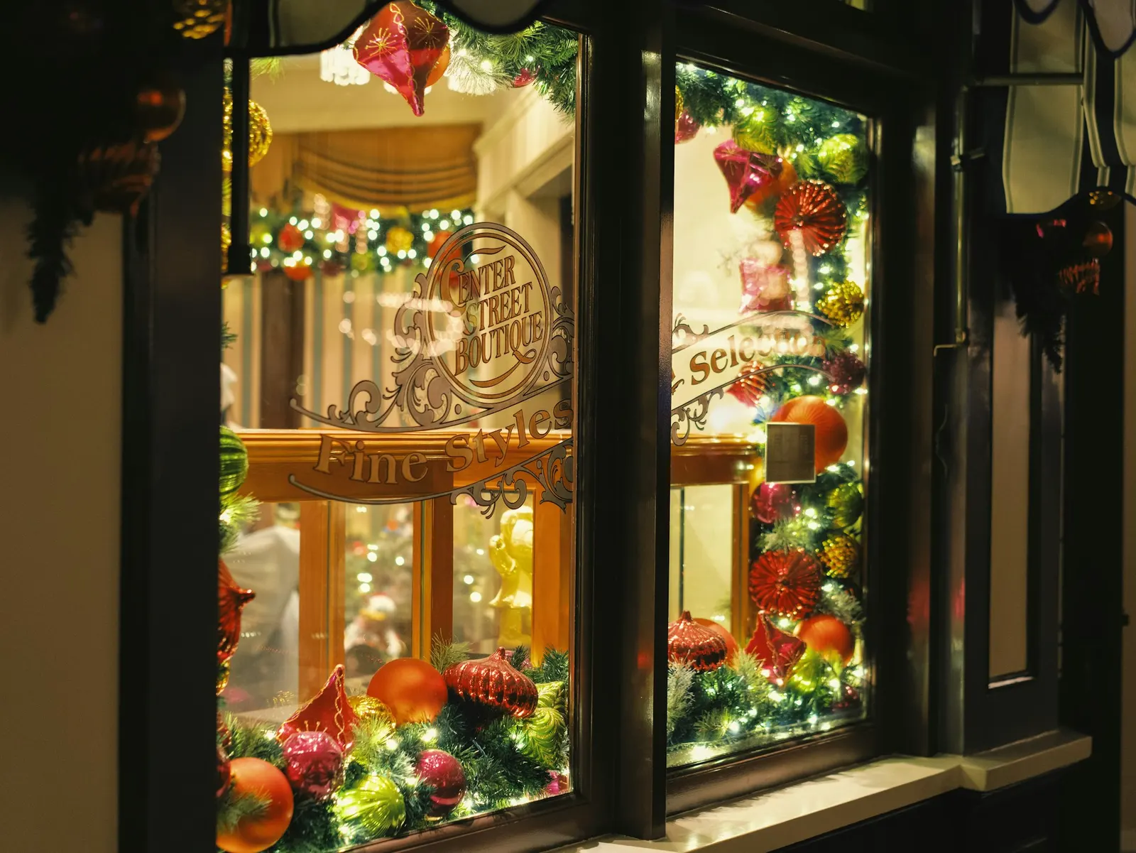 Shop window decorated for Christmas with garlands, ornaments, and warm lights at night