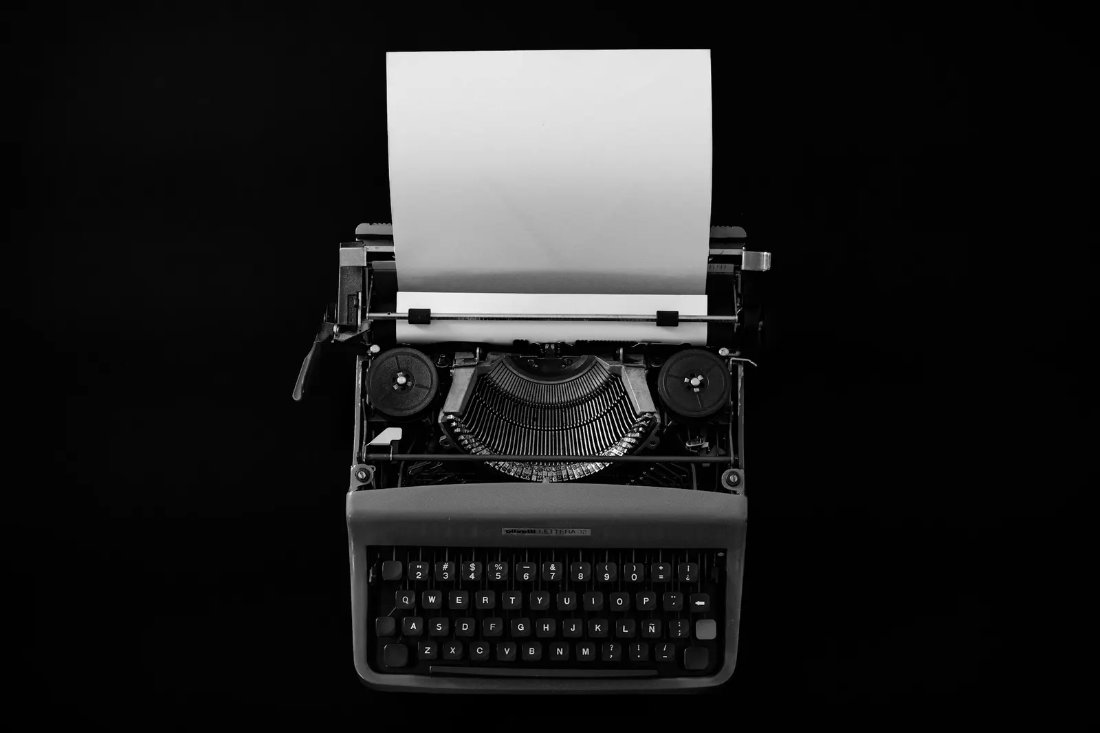Vintage typewriter with a blank sheet of paper on a black background