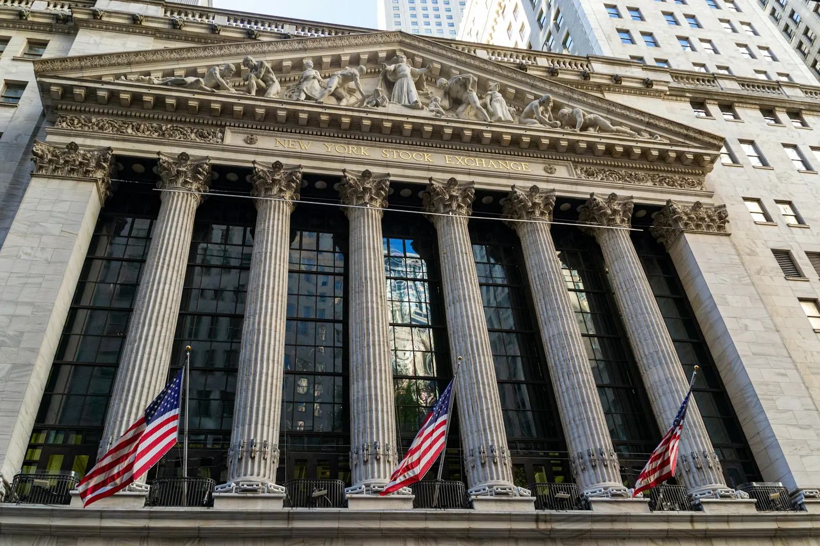 The columned facade of the New York Stock Exchange on Broad Street in Manhattan, with American flags hanging between the columns