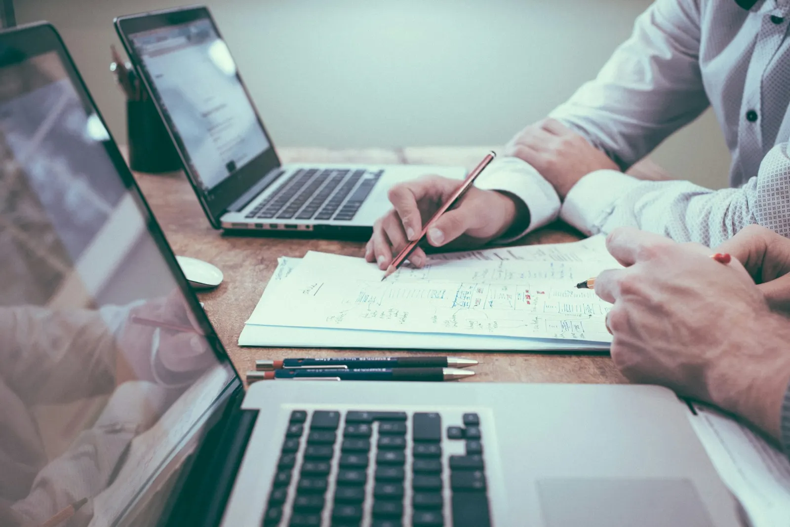Hands reviewing printed charts with a pencil beside a laptop during a planning session