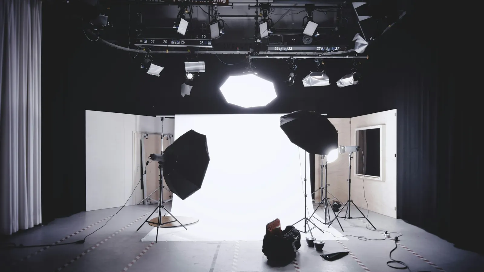 A photography and video studio with softbox lights and a white backdrop, set up for filming