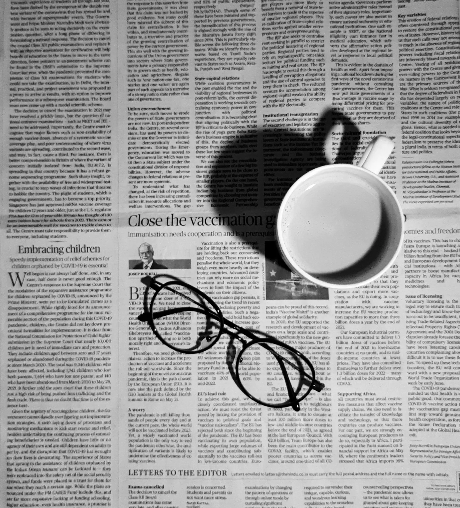 A cup of coffee and a pair of glasses resting on the editorial page of a newspaper