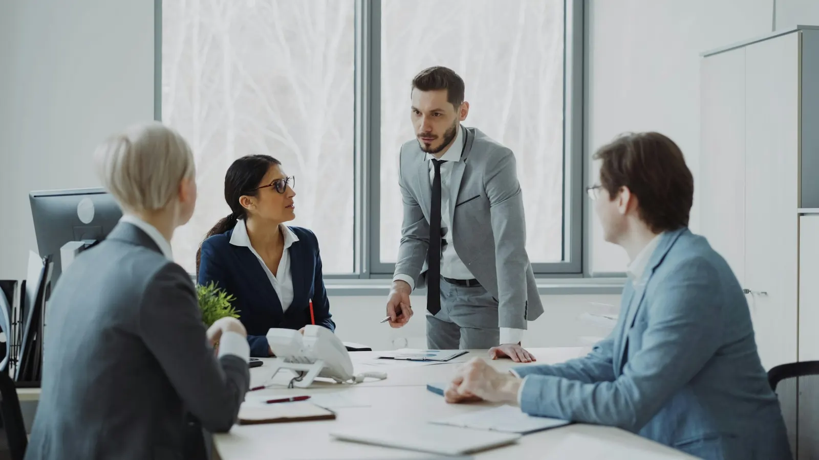 An executive standing to lead a discussion around a conference table